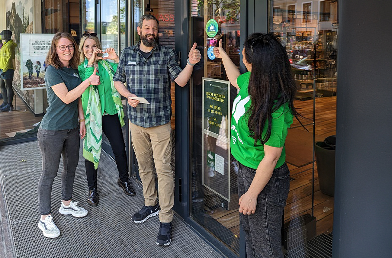 Foto: cleanffm-Team startet Kooperation mit Globetrotter und bringt Aufkleber am Eingang an.