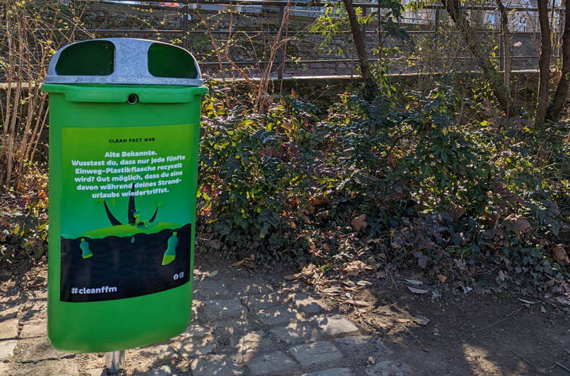Foto: Grüner cleanffm-Mülleimer mit Clean-Fact-Design und informativem Aufdruck.