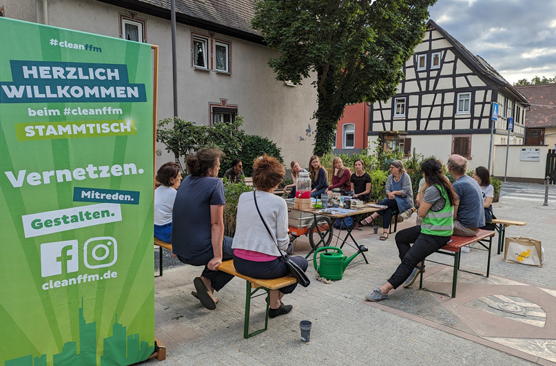 Foto: cleanffm-Stammtisch mit Teilnehmenden im Austausch bei einem Treffen im öffentlichen Raum.