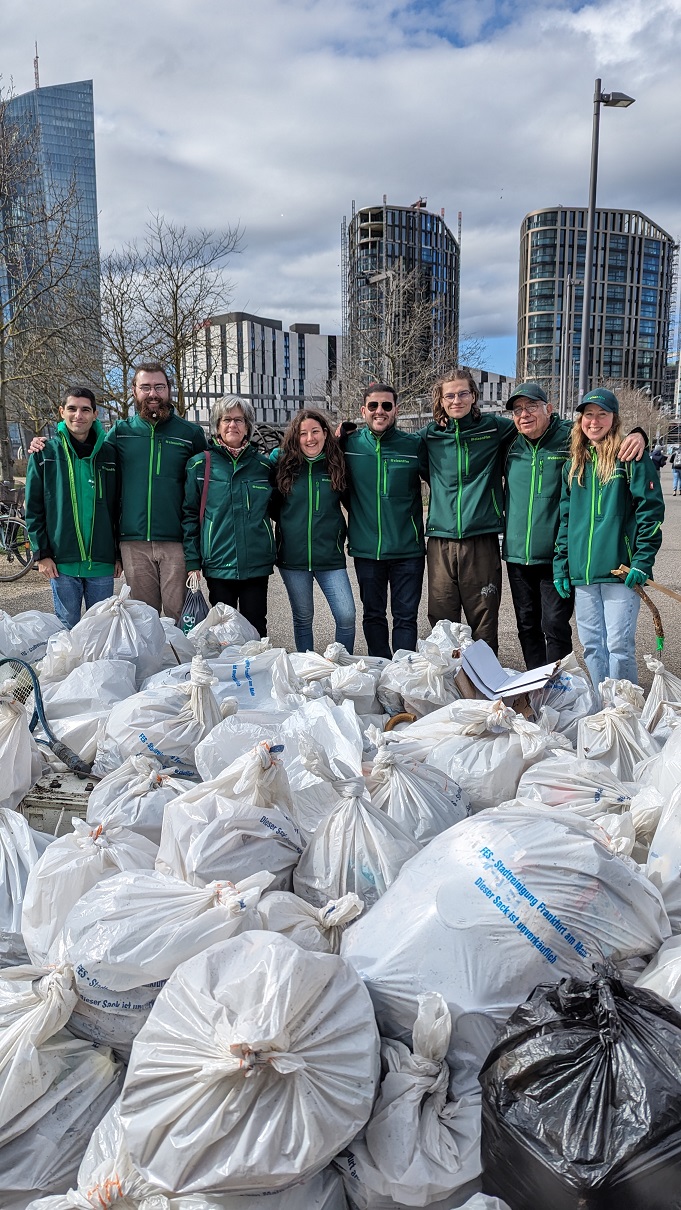 Foto: Gruppe von Sauberkeitsbotschafter/innen steht hinter vielen gefüllten Müllsäcken im Freien